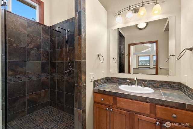 full bath with plenty of natural light, tiled shower, and vanity