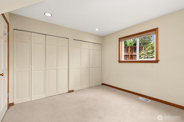 unfurnished bedroom featuring light carpet, baseboards, two closets, and recessed lighting