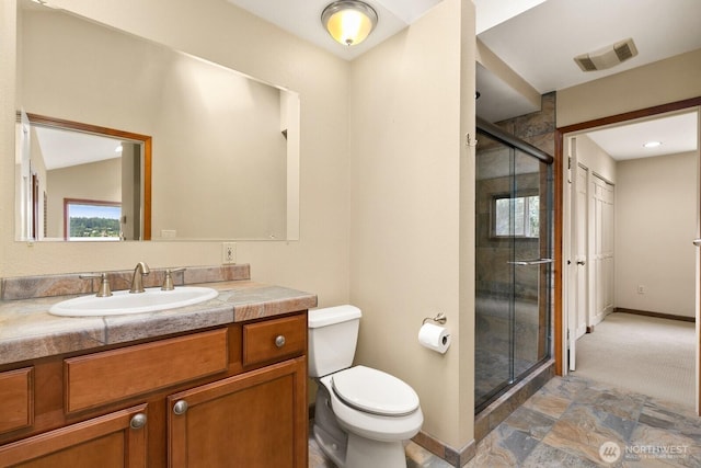 bathroom with baseboards, toilet, a shower stall, and vanity