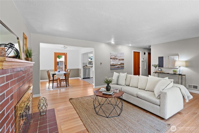 1510 N Mason Ave, Tacoma, WA 98406 - living room featuring a fireplace, wood finished floors, a textured ceiling, and baseboards