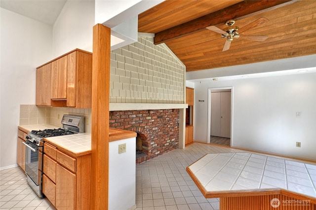 kitchen with gas range, tile counters, light tile patterned floors, and a ceiling fan