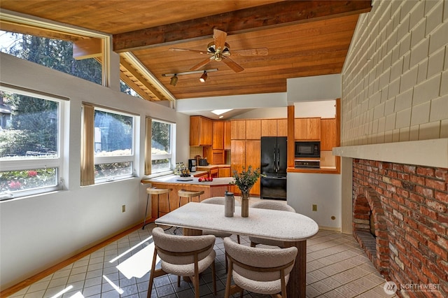 kitchen with black appliances, brown cabinetry, light tile patterned flooring, beam ceiling, and wood ceiling