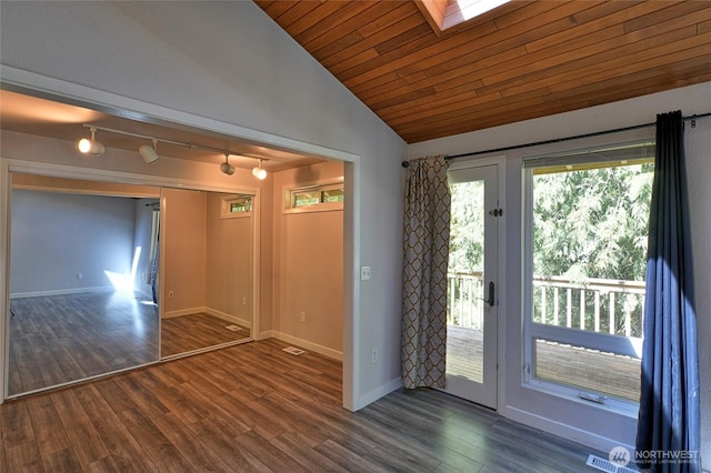 spare room with track lighting, dark wood-type flooring, a skylight, vaulted ceiling, and baseboards