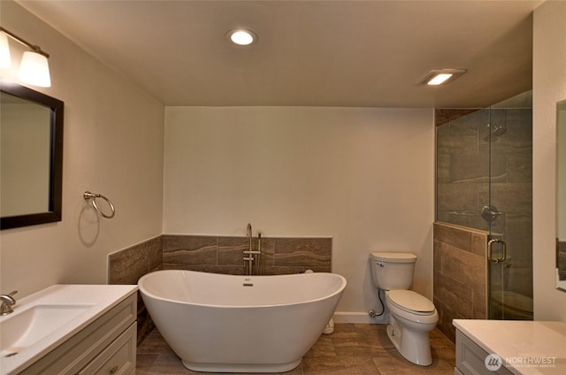 full bath featuring a stall shower, toilet, a freestanding tub, vanity, and recessed lighting