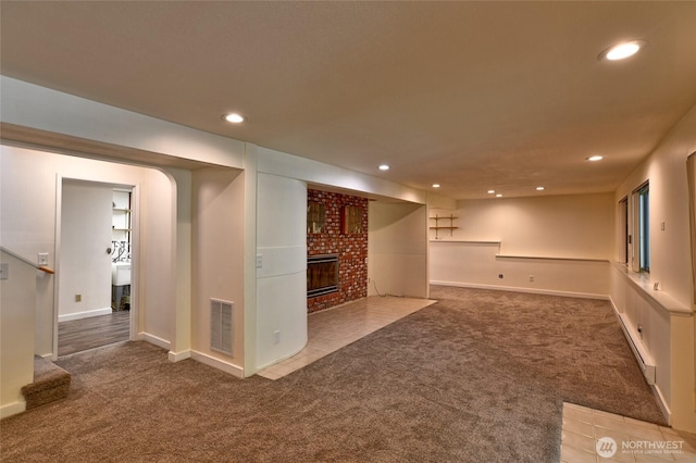 finished basement featuring carpet, recessed lighting, a fireplace, baseboards, and a baseboard heating unit