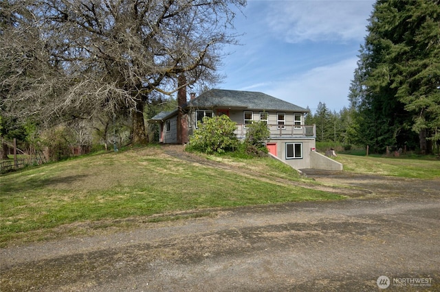 view of front of home with driveway, a front yard, and a wooden deck