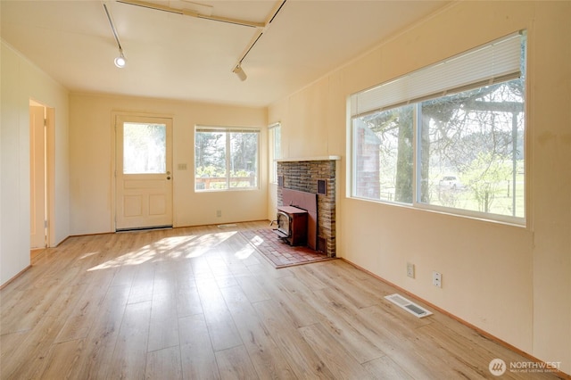 unfurnished living room with rail lighting and light wood-style flooring