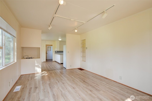 unfurnished living room featuring track lighting, light wood-type flooring, and baseboards