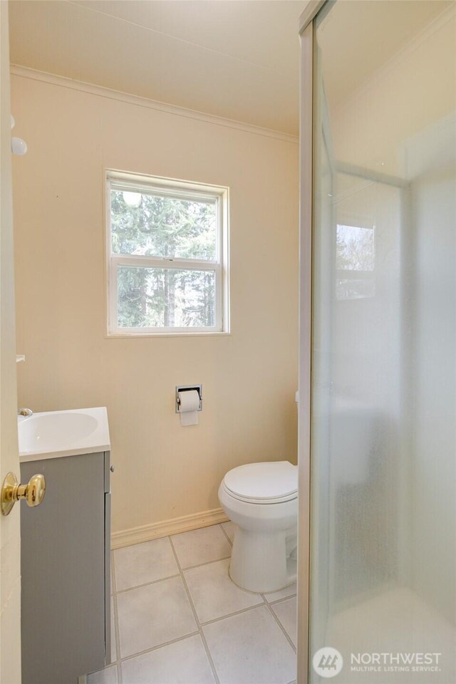 bathroom featuring a stall shower, vanity, tile patterned flooring, toilet, and baseboards