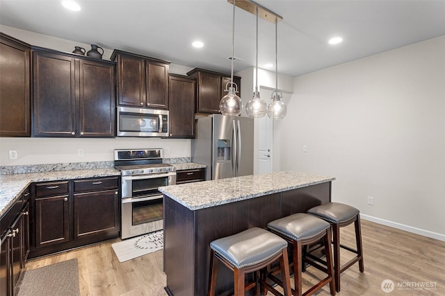 14123 67th Ave E, Puyallup, WA 98373 - kitchen featuring stainless steel appliances, a breakfast bar, dark brown cabinets, light wood finished floors, and recessed lighting