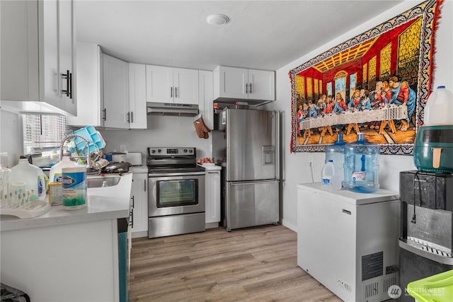 810 SW 124th St, Burien, WA 98146 - kitchen with appliances with stainless steel finishes, under cabinet range hood, white cabinets, light countertops, and light wood finished floors
