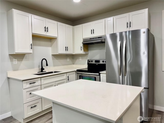 810 SW 124th St, Burien, WA 98146 - kitchen with appliances with stainless steel finishes, a sink, under cabinet range hood, wood finished floors, and white cabinetry