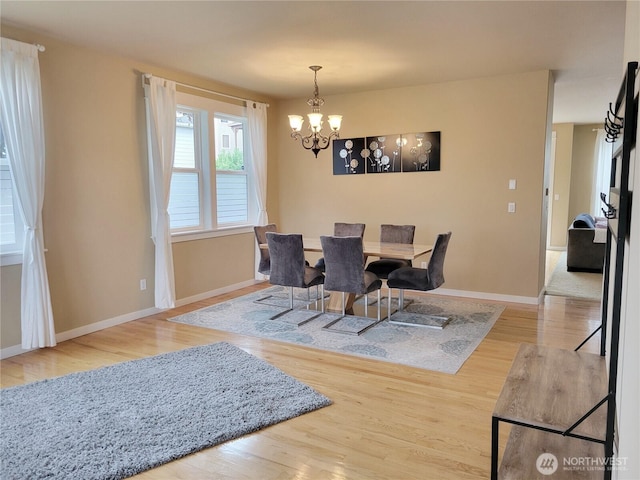 dining room featuring a chandelier, wood finished floors, and baseboards