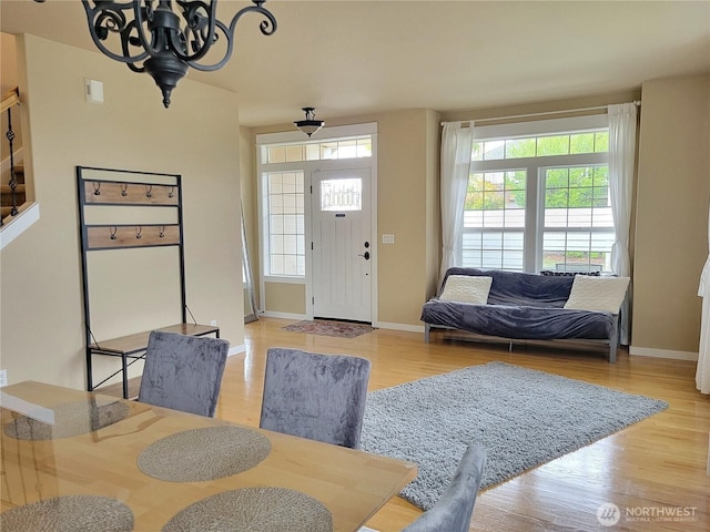 foyer with light wood-type flooring, healthy amount of natural light, baseboards, and a chandelier