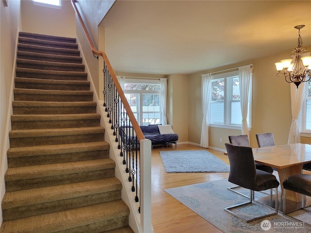 dining space with stairway, a chandelier, wood finished floors, and healthy amount of natural light