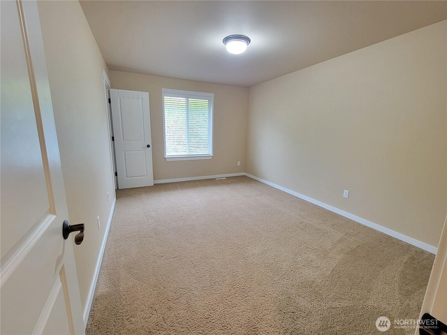 empty room with light colored carpet and baseboards