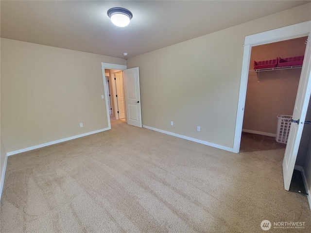 unfurnished bedroom featuring carpet floors, baseboards, and a walk in closet