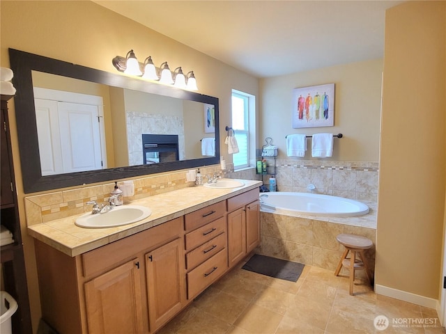 full bath featuring a garden tub, double vanity, tile patterned flooring, and a tiled fireplace