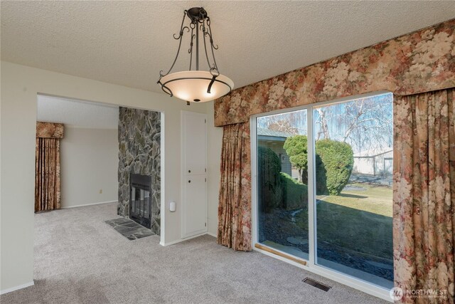 3579 NW Dodson Rd, Ephrata, WA 98823 - unfurnished living room featuring carpet floors, a stone fireplace, and a textured ceiling