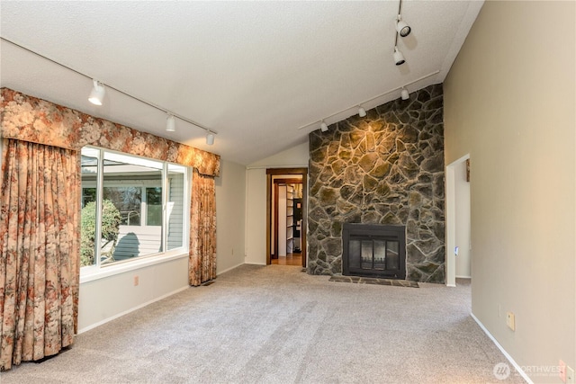 3579 NW Dodson Rd, Ephrata, WA 98823 - unfurnished living room with track lighting, carpet flooring, a fireplace, lofted ceiling, and a textured ceiling