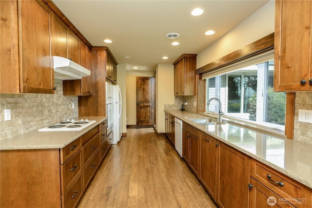 3579 NW Dodson Rd, Ephrata, WA 98823 - kitchen featuring under cabinet range hood, a sink, brown cabinetry, white appliances, and light wood-style flooring
