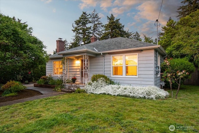 view of front of house featuring a lawn and a chimney