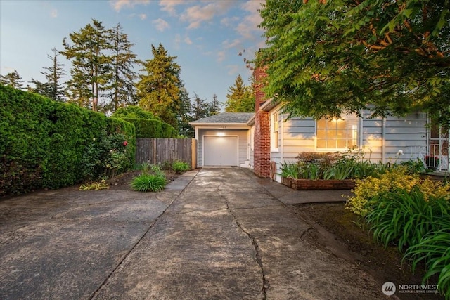 garage with concrete driveway and fence