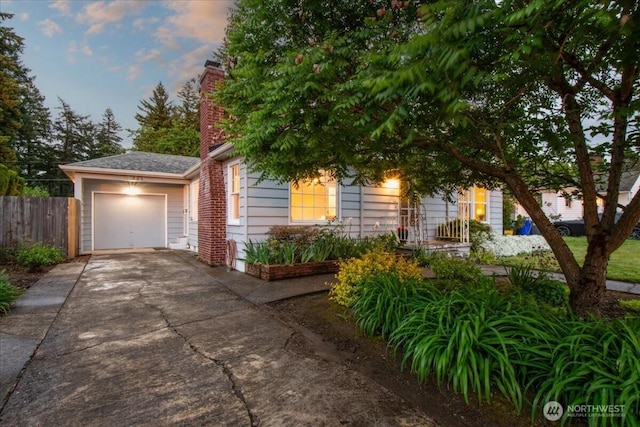 obstructed view of property featuring driveway, fence, a garage, and a chimney