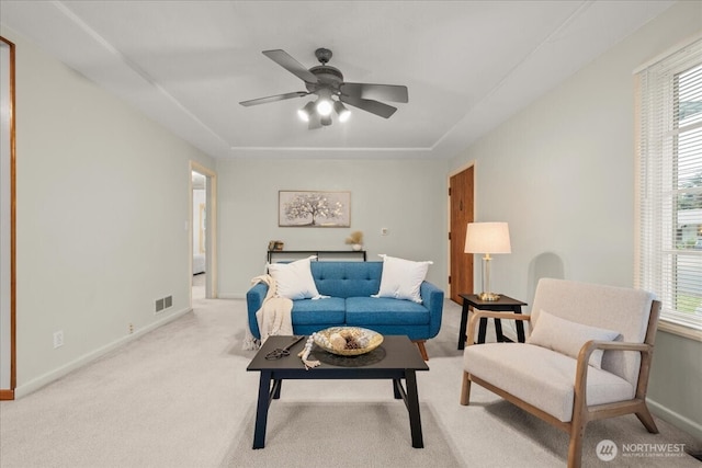 carpeted living area with a ceiling fan, plenty of natural light, and baseboards