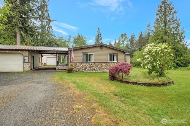 ranch-style home with an attached garage, stone siding, a front lawn, driveway, and metal roof