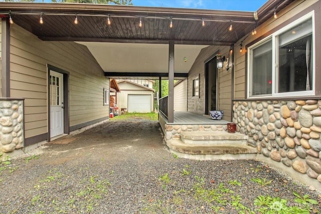 view of patio featuring a carport, an outdoor structure, and driveway