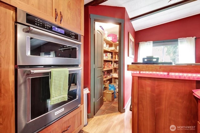 kitchen with stainless steel double oven and lofted ceiling