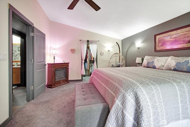 carpeted bedroom with a fireplace, vaulted ceiling, ceiling fan, and connected bathroom