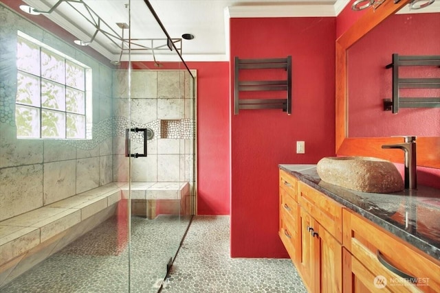 full bath featuring a tile shower, vanity, and baseboards
