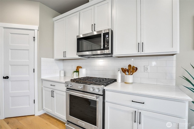 17711 11th Ave NE, Arlington, WA 98223 - kitchen with appliances with stainless steel finishes, light wood-style floors, white cabinetry, and decorative backsplash