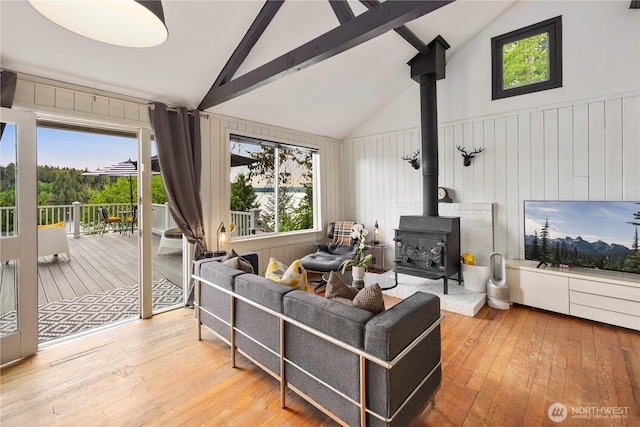 living area with a wood stove, hardwood / wood-style flooring, plenty of natural light, beamed ceiling, and high vaulted ceiling