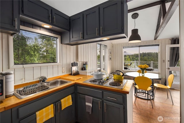 kitchen featuring wood counters, stainless steel electric stovetop, a sink, wood finished floors, and a peninsula