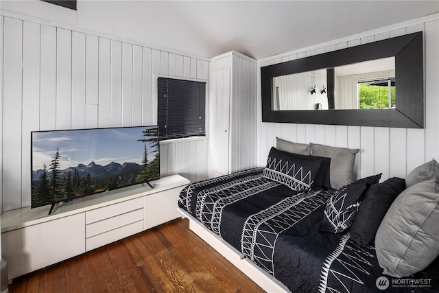 bedroom with hardwood / wood-style flooring, vaulted ceiling, and wooden walls