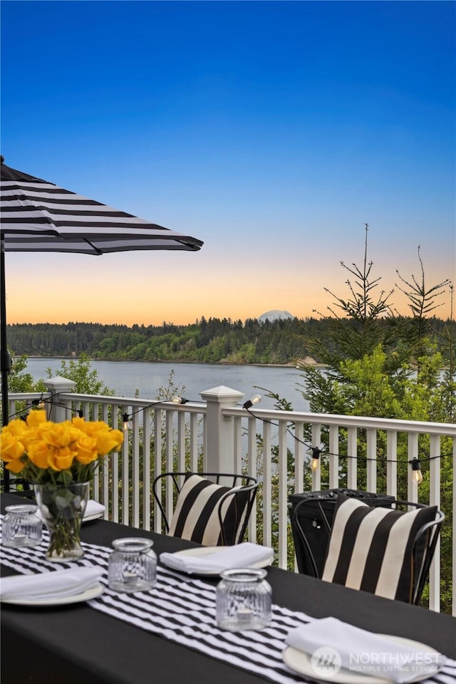 balcony at dusk featuring a water view