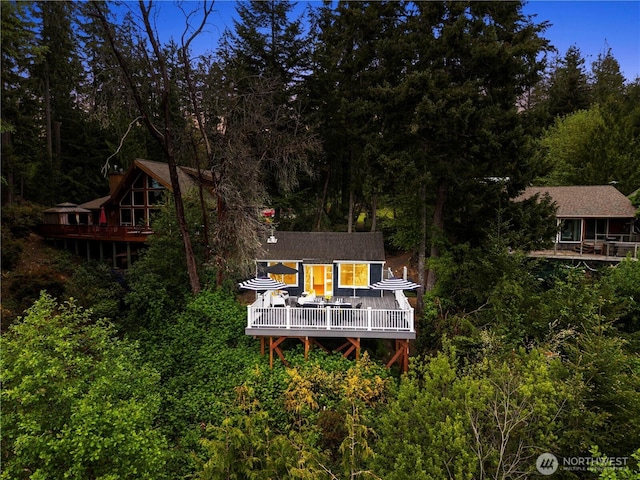 rear view of property with a wooden deck and a wooded view