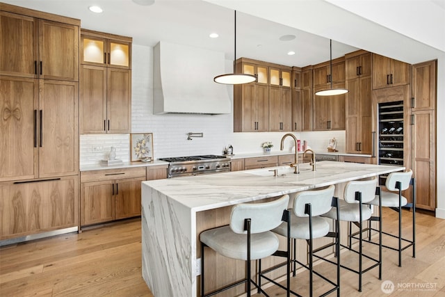 kitchen featuring double oven range, light wood-type flooring, wall chimney exhaust hood, backsplash, and glass insert cabinets