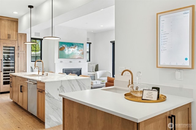 kitchen featuring a sink, dishwasher, light wood-style floors, an island with sink, and recessed lighting