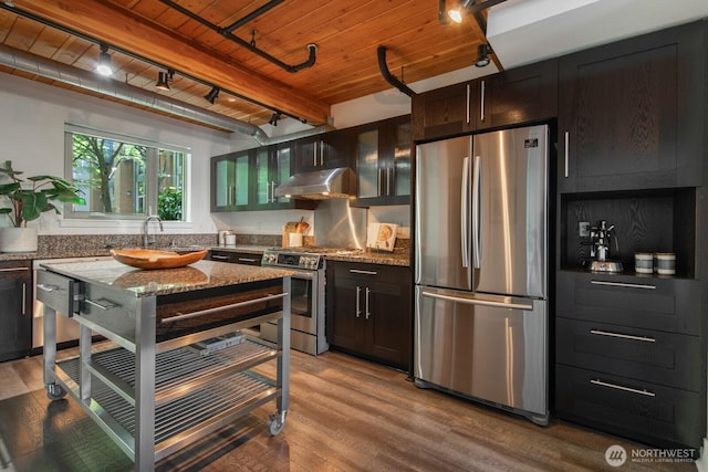 530 Broadway E Unit 124, Seattle, WA 98102 - kitchen with appliances with stainless steel finishes, track lighting, wood ceiling with exposed beams, under cabinet range hood, and stone countertops
