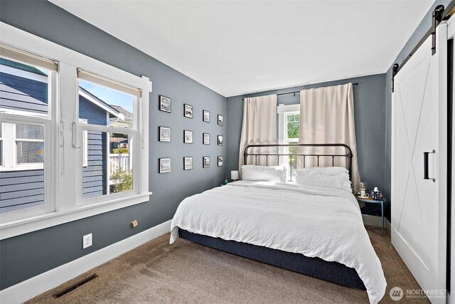 6311 46th Ave SW, Seattle, WA 98136 - bedroom featuring a barn door, dark colored carpet, and baseboards