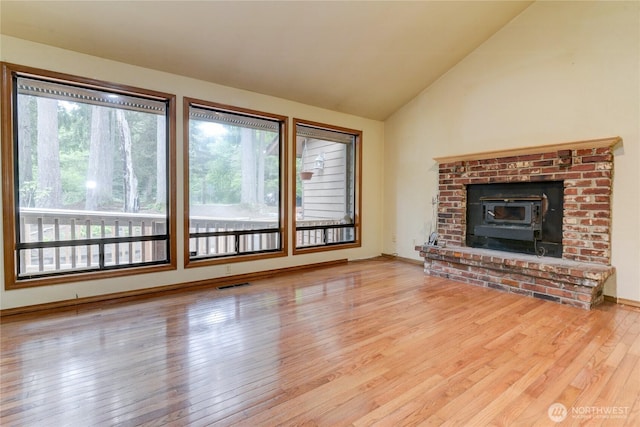 6605 Cooper Point Rd NW, Olympia, WA 98502 - unfurnished living room featuring wood finished floors, lofted ceiling, and a wood stove