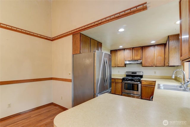 6605 Cooper Point Rd NW, Olympia, WA 98502 - kitchen with appliances with stainless steel finishes, under cabinet range hood, a sink, light countertops, and light wood finished floors