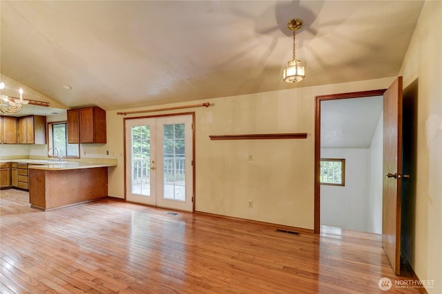 6605 Cooper Point Rd NW, Olympia, WA 98502 - kitchen with light wood-style floors, brown cabinets, light countertops, a peninsula, and french doors