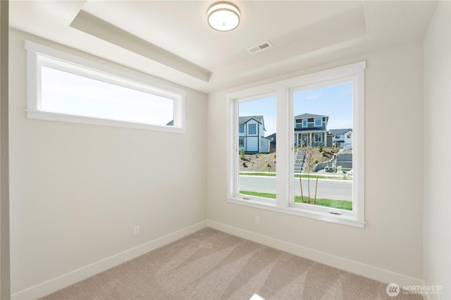carpeted empty room with a tray ceiling and baseboards