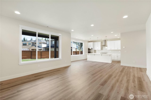 unfurnished living room featuring light wood-style flooring, baseboards, and recessed lighting
