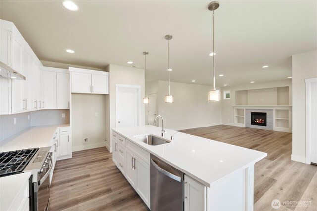 kitchen with a sink, appliances with stainless steel finishes, light wood-style flooring, white cabinets, and recessed lighting